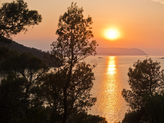 Fototapeta na wymiar Sunset behind Skiathos island, a view from the road above Kastani beach, island of Skopelos, Greece