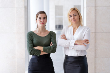 Business team of two young female professionals. Successful young business women posing with arms...