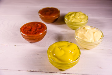 Different sauces in glass bowls on wooden table