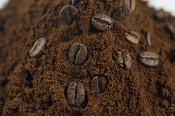 Macro of a coffee bean in roasted coffee grounds.