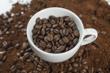 Macro of a coffee bean in roasted coffee grounds.