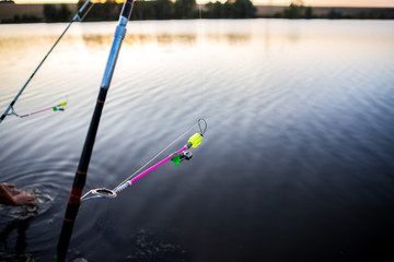 Bells for fish bites on fishing rod against background of lake. Bite alarm. Feeder carp fishing.