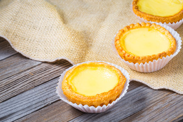 Egg tarts and eggs on burlap and wooden surface 