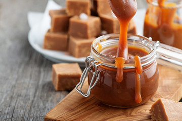Homemade salted caramel sauce in jar on rustic wooden table. - 219467611