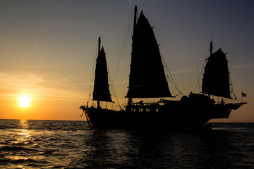 Old junk style sailboat sailing into the sunset of the Andaman Sea in Thailand