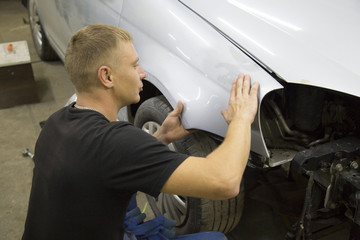 auto mechanic worker painting car in a paint chamber during repair work