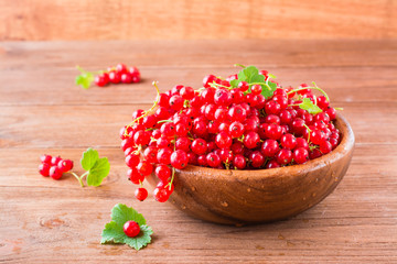 A bunch of fresh red currants in a wooden plate on a table
