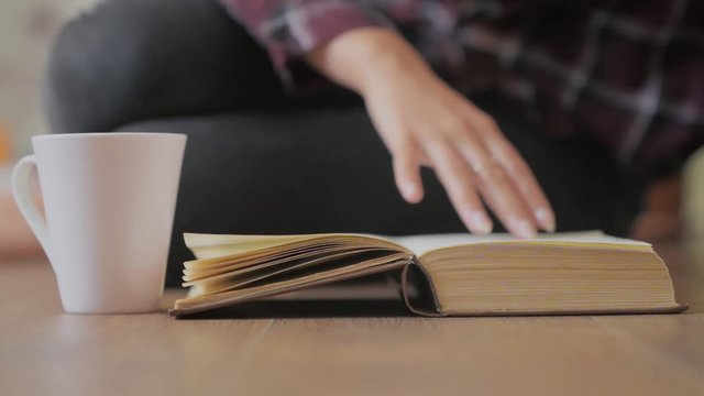 Girl is reading a paper book and drinking coffee, studing dtudent or leisure concept