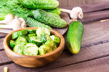 Freshly salted cucumber pickled with garlic and dill in a wooden plate. Rustic style
