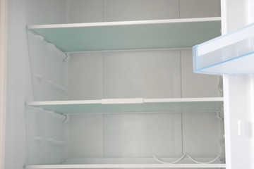 Empty white shelves in refrigerator. Diet and hunger concept.