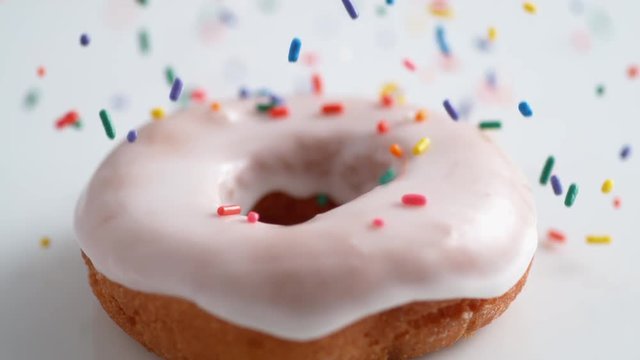 Sprinkling candy chocolate on frosted doughnut. Shot with high speed camera, phantom flex 4K. Slow Motion.
