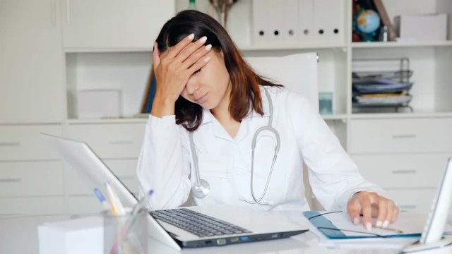 Upset practicioner girl is working with documents and laptop  in clinic