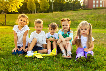 four babies are sitting with toys on a green glade