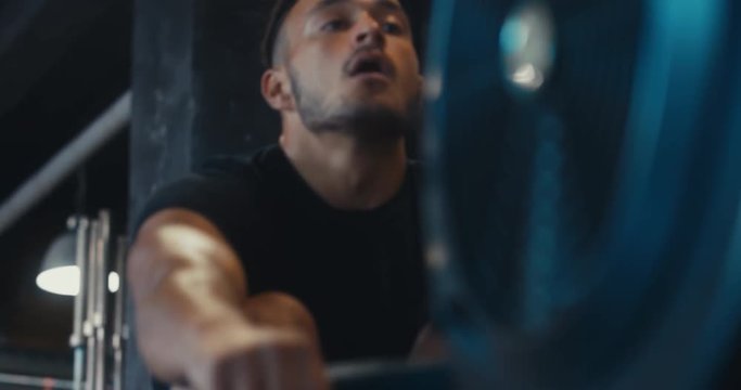 CU portrait of Caucasian male athlete working out in a gym, using rowing ergometer indoors. 4K UHD