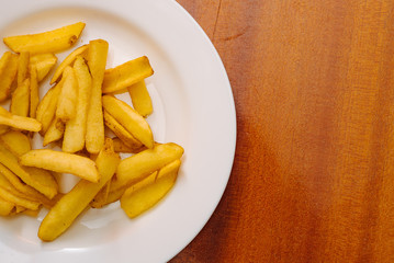French potatoes fries in the white plate on wooden background.