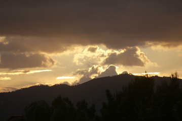 Cielo oscuro nublado, cubierto de nubes, montañas, rayos y luz dorada de sol al atardecer desde zona residencial, Marratxí, Mallorca, Islas Baleares. Atmósfera oscura y lluviosa en día de invierno.