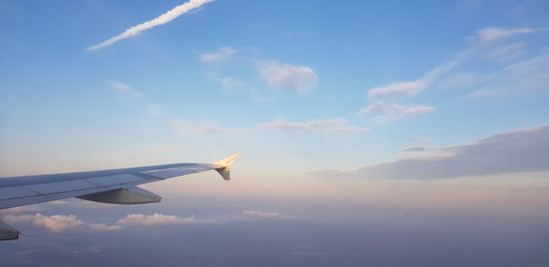 View of the wing of the plane, a contrail of another plane and the beautiful sky