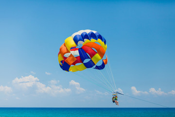 Couple of tourists flying on a colorful parachute