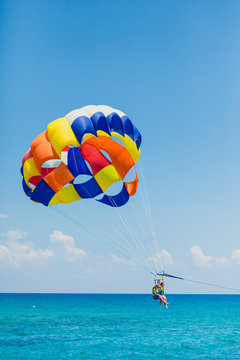 Couple of tourists flying on a colorful parachute