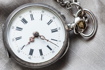 old pocket watch on gray textile background