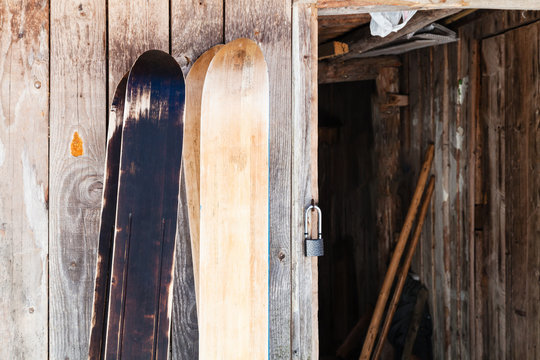 two pairs of wide forest skis near wooden shed
