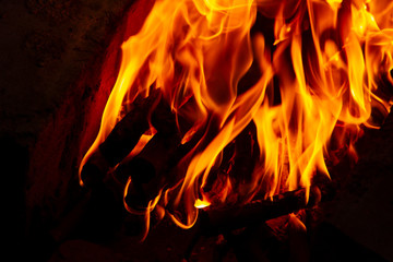 Fire from charred logs. Fire burns in the dark. Fire on a dark background. The flame from the campfire.