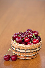 Fototapeta na wymiar Red Ripe Cherries in a basket on a wood table