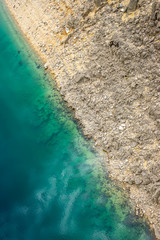 A picturesque place where transparent turquoise water meets a stony shore.