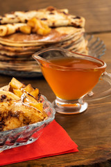 Round fried pancakes with apple s and honey, vertical frame, wooden background.