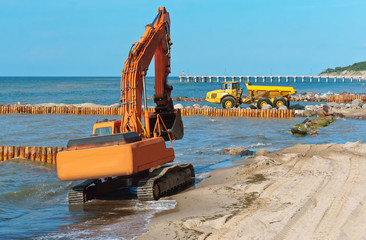 Construction of breakwaters in the sea. Construction equipment and machinery on the seashore.