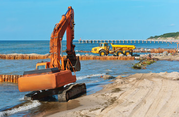 Construction of breakwaters in the sea. Construction equipment and machinery on the seashore.
