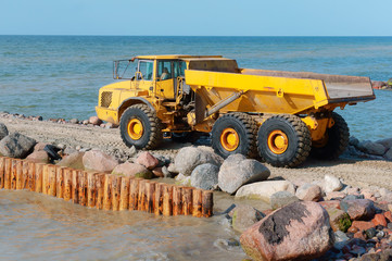 Construction of breakwaters in the sea. Construction equipment and machinery on the seashore.