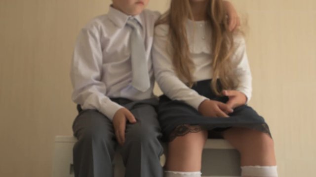 Back to school. Portrait of happy children with blue eyes and blond hair in school uniform. Boy and a preschool girl sitting on washing machine at home in bathroom. Shallow focus