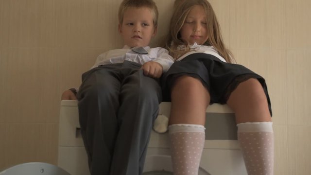 Back to school. Portrait of happy children with blue eyes and blond hair in school uniform. Boy and a preschool girl sitting on washing machine at home in bathroom. Shallow focus