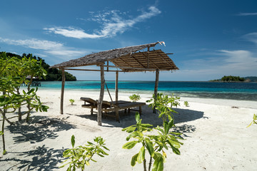 Tropical sand beach resort on remote Malenge island, part of Togean archipelago with shelter and deckchair, Lestari, Indonesia