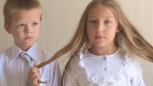Close-up portrait of happy children with blue eyes and blond hair in school uniform. Boy and girl preschoolers on wind. Breeze plays with girl's hair and clothers. Old vintage style. Shallow focus