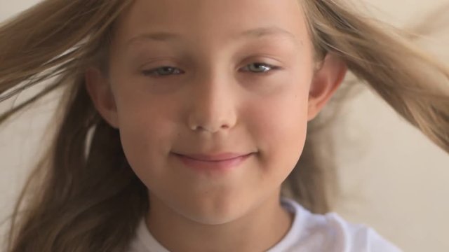 Close Up Portrait of happy young  girl with blue eyes and blond hair. Standing on Wind. Breeze is playing with girl's hair. Stormy weather, autumn, winter, spring. Old style vintage. Shallow focus