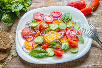 Sliced heirloom tomatoes, crisp cucumbers with chopped red onion, chives drizzled with olive oil and added basil leaves.