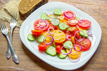 Sliced heirloom tomatoes, crisp cucumbers with chopped red onion, chives drizzled with olive oil and added basil leaves.