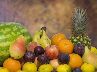 fruit on wooden table, pineapple orange, pear, mandarin, banana, plum, apple, watermelon and peach