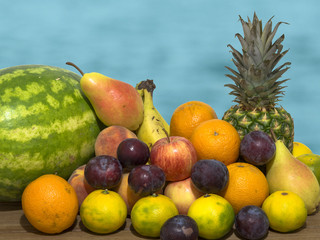 fruit on wooden table, pineapple orange, pear, mandarin, banana, plum, apple, watermelon and peach