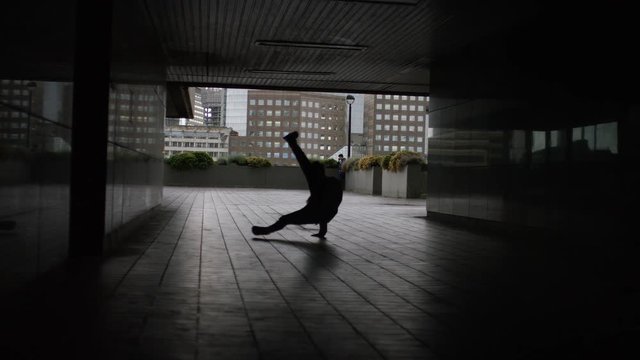Male dancer doing breakdance moves in a tunnel, in slow motion 