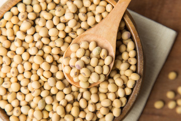 Soybeans in wooden bowl and spoon putting on linen and wooden background.