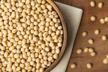 Soybeans in wooden bowl putting on linen and wooden background.