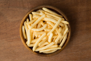 Top view of french fries or potato fry in wooden bowl putting on linen and wooden background.