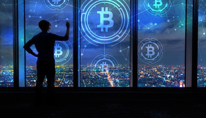 Bitcoin with man writing on large windows high above a sprawling city at night