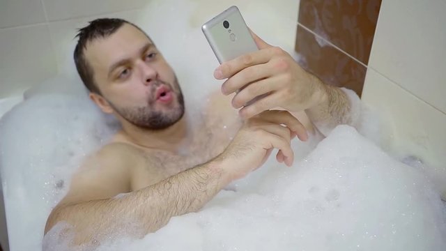 Top view of a handsome adult man lying in bubble bath.