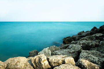 Long-exposure photo of water along rocky lake coastline.