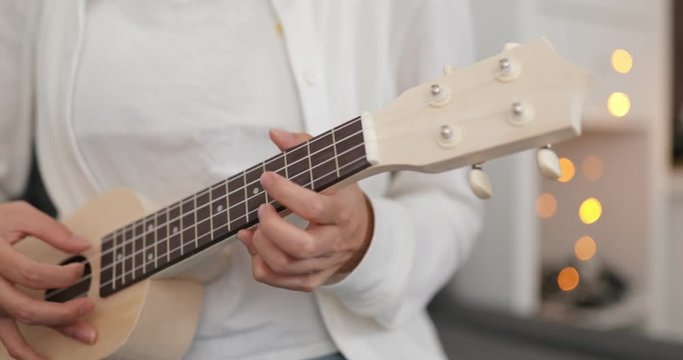 Woman practicing ukulele at home