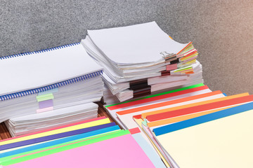 Pile of unfinished paperwork on teacher's desk waiting to be managed. Stack of